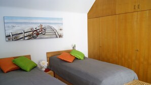 Une chambre avec deux lits, une armoire en bois et un tableau représentant un vélo sur un pont.