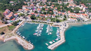 An aerial view of a coastal marina with numerous boats docked, surrounded by residential buildings and a sandy beach area. - Apartment Nidisa by Interhome (Krk/Čižići)