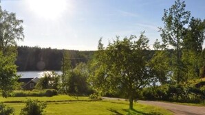 A rural landscape with a house, a lake, and a road.
