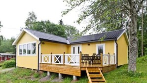 A yellow building with a wooden deck, a staircase, and a fenced outdoor area.
