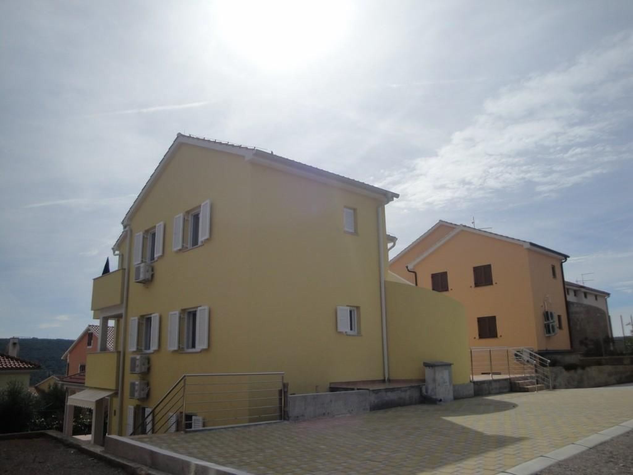 A yellow building with a flat roof and a small balcony.