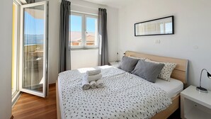 Een slaapkamer met een bed, nachtkastje, raam met gordijnen en een fotokader aan de muur.