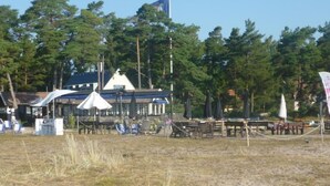 En fastighet vid stranden med en stor byggnad, utomhusmöbler och en flagga.