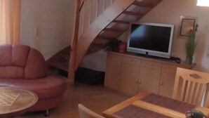 A cozy living room with a red sofa, wooden dining table, and a TV on a wooden cabinet. - mit überdachter Terrasse und Carport by Interhome (Walsrode)