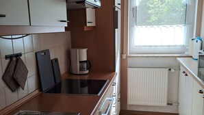 A modern kitchen with a built-in stove, a coffee maker, and a window with a view of greenery. - mit überdachter Terrasse und Carport by Interhome (Walsrode)