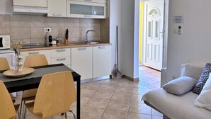 A modern kitchen with white cabinets, a microwave, and a dining area with a table and chairs. - Apartment PintaDeSol by Interhome (Krk/Čižići)
