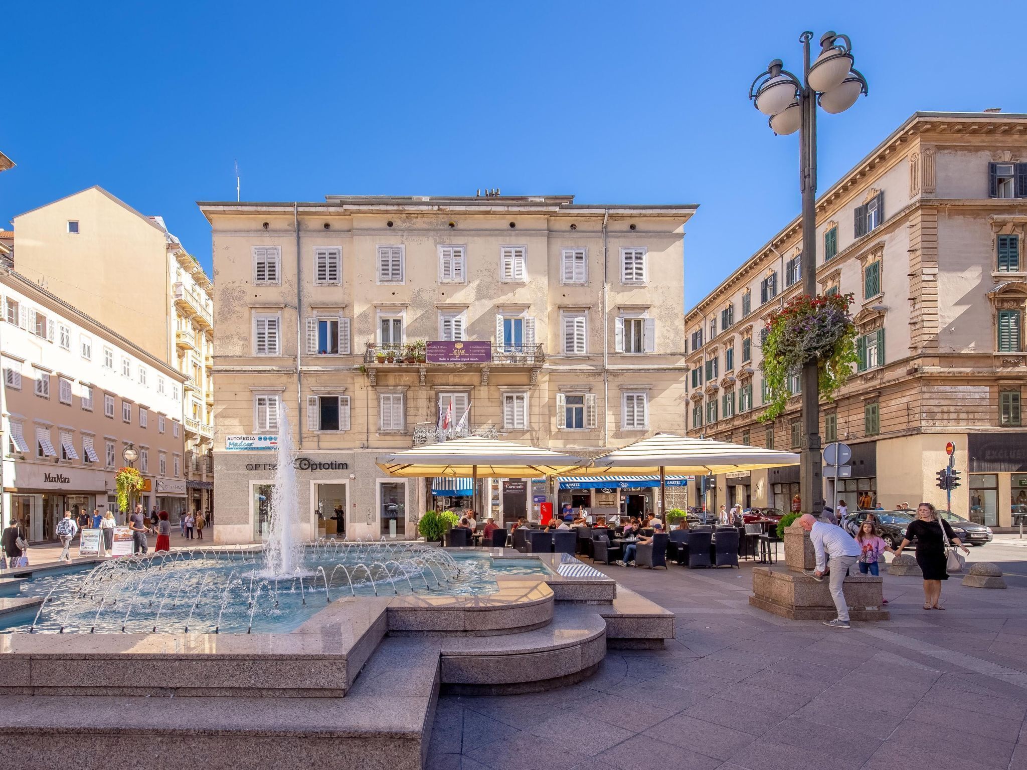 A public square with a fountain, outdoor seating, and historic buildings.