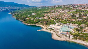 An aerial view of a coastal town with a prominent building featuring a large dome and a modern glass structure.