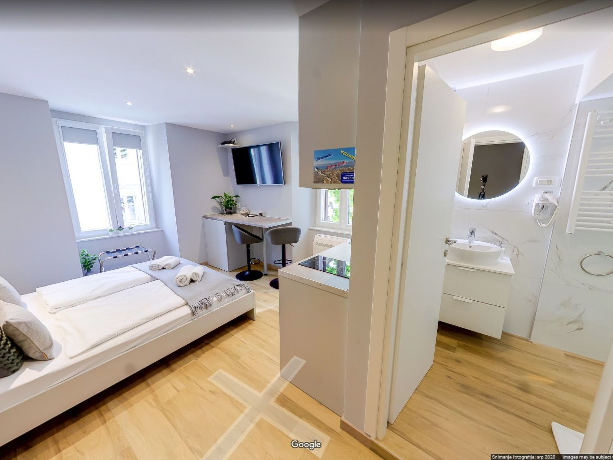 A modern hotel room with a bed, desk, and bathroom.