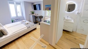 A modern hotel room with a bed, desk, and bathroom.