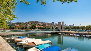 A marina with several boats docked, a bridge, and buildings in the background.