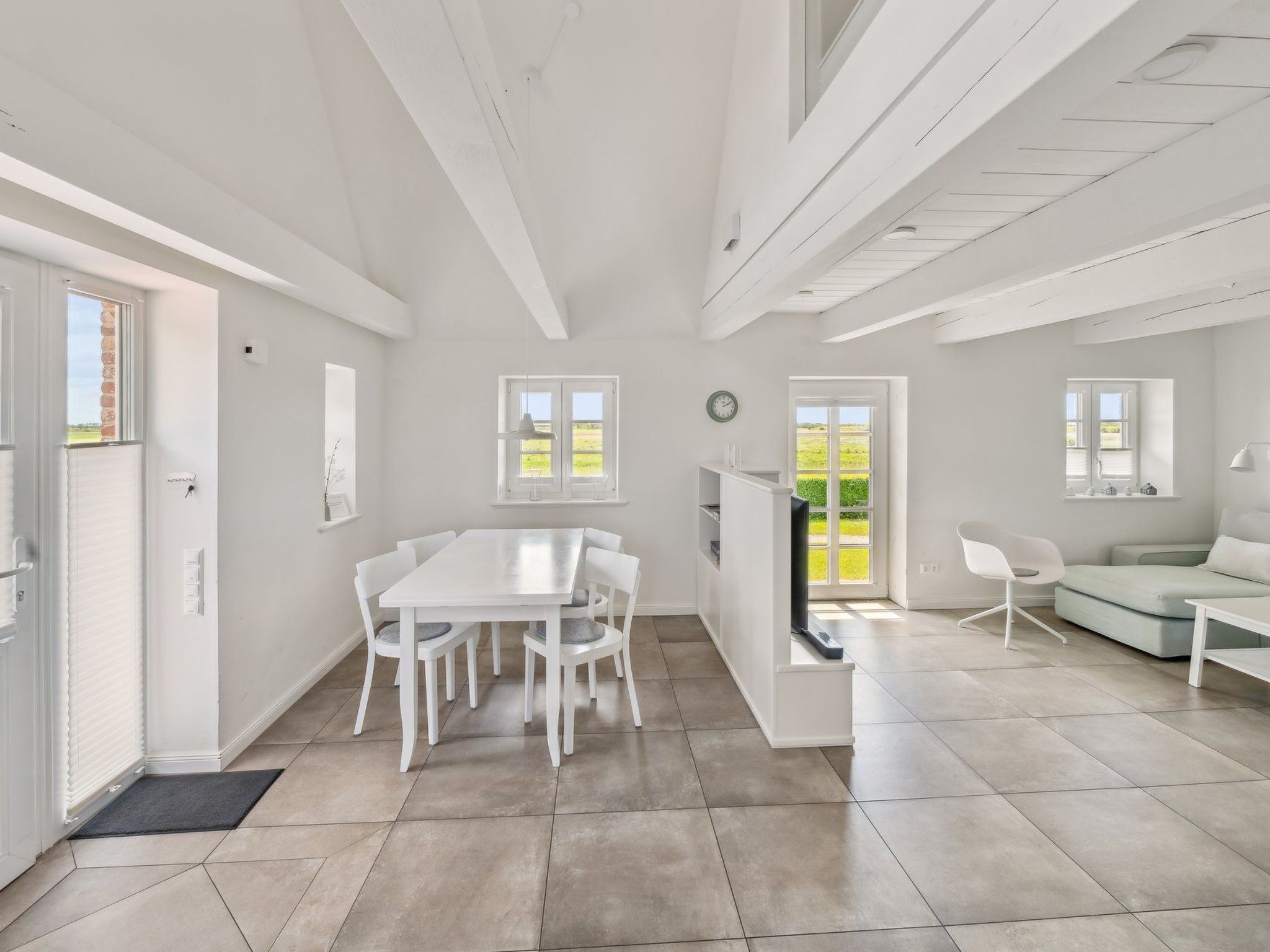 A bright, open-plan living space with a dining area, a seating area, and a kitchen.