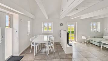 A bright, open-plan living space with a dining area, a seating area, and a kitchen.