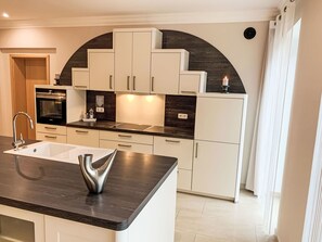 A modern kitchen with white cabinetry, a black countertop, and a stainless steel sink. - Modern eingerichtete Suite mit Terrasse by Interhome (Elskop)