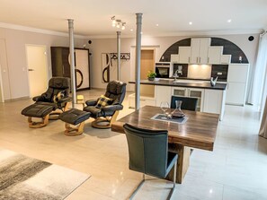 A modern living room with a wooden dining table, two leather sofas, and a kitchen in the background. - Modern eingerichtete Suite mit Terrasse by Interhome (Elskop)