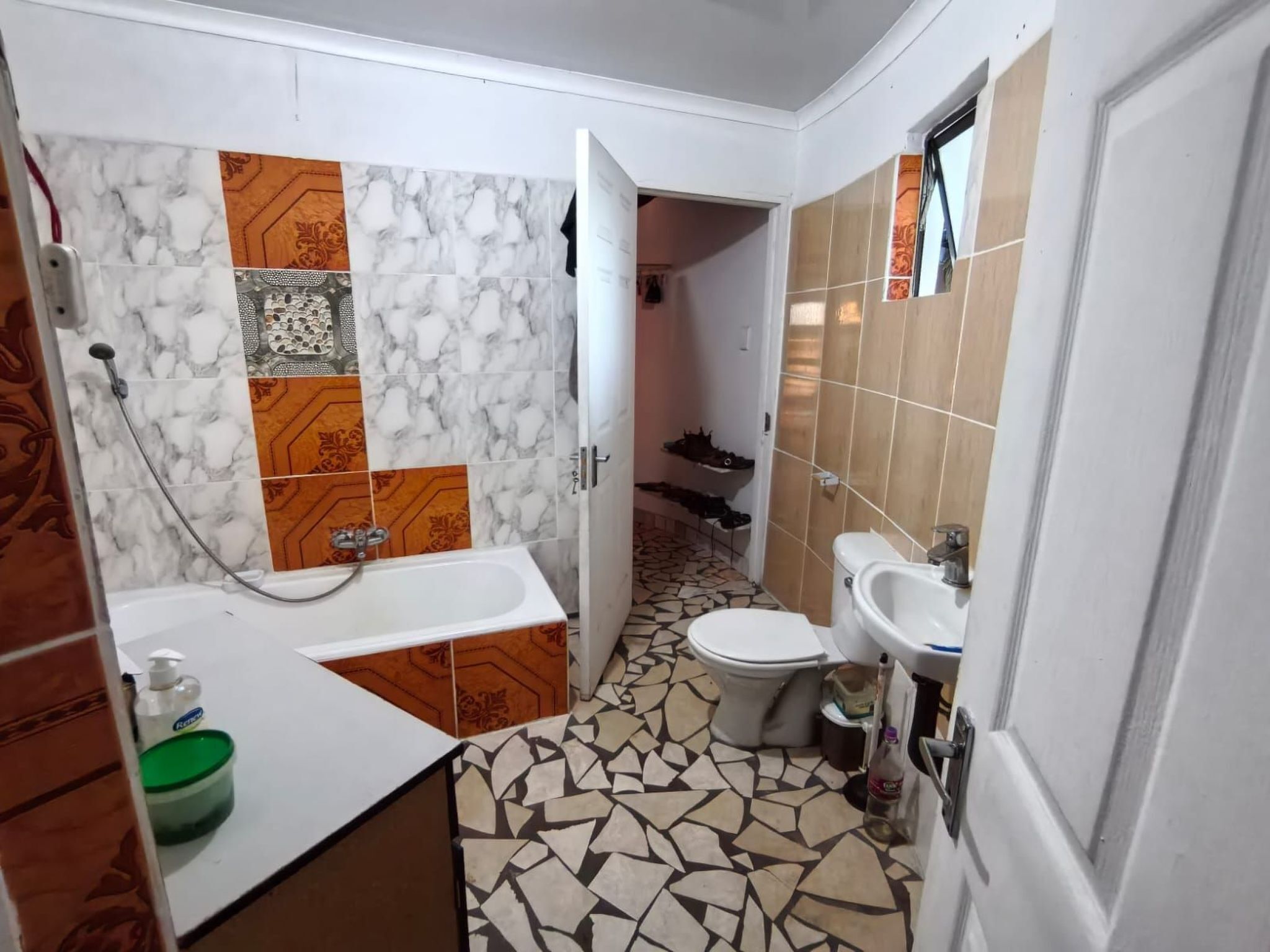 Un baño con pared de mármol, lavamanos, inodoro y ducha.