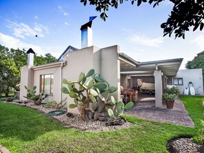 A modern house with a patio, a cactus garden, and a garage.