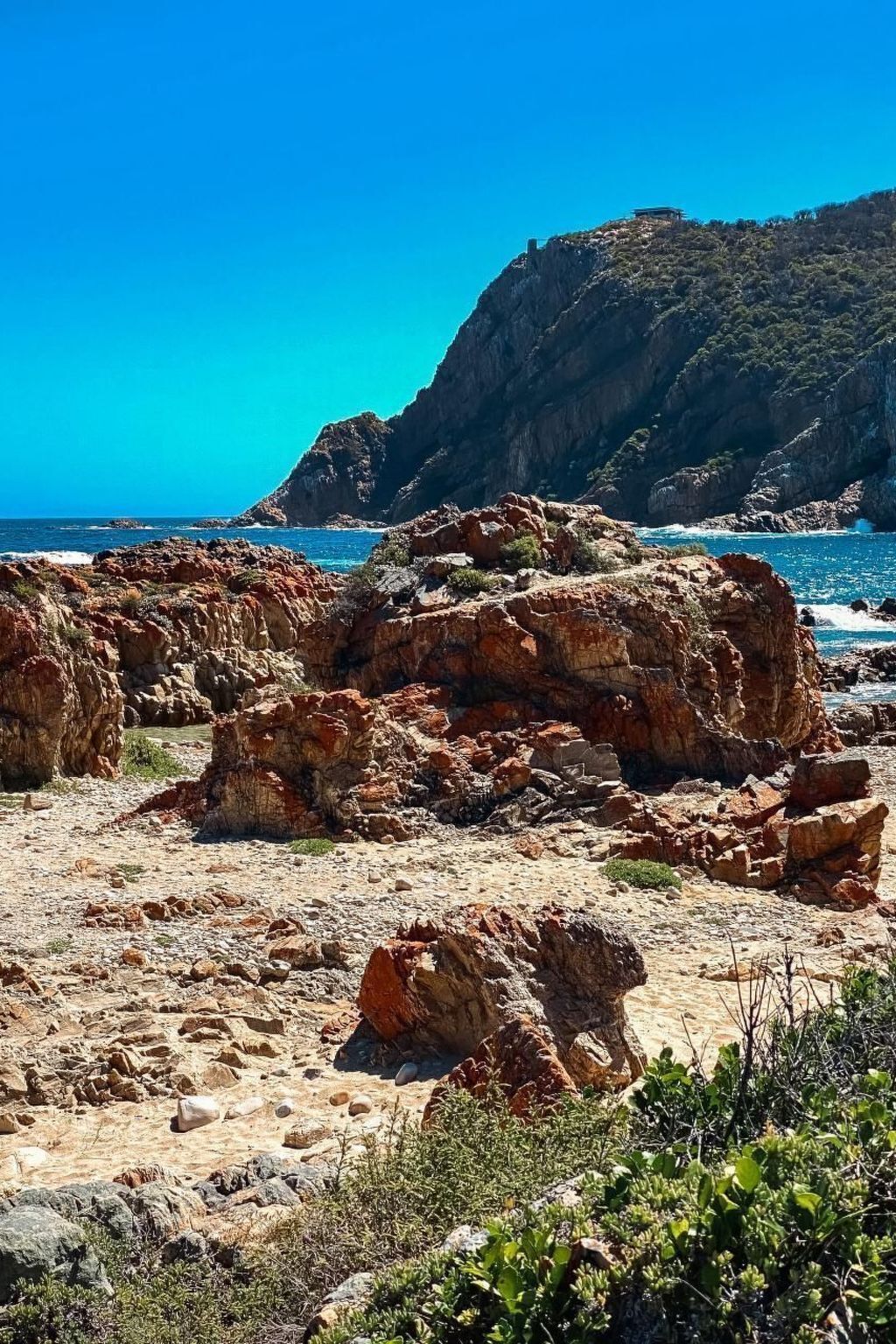 A rocky coastal landscape with rugged terrain and sparse vegetation.