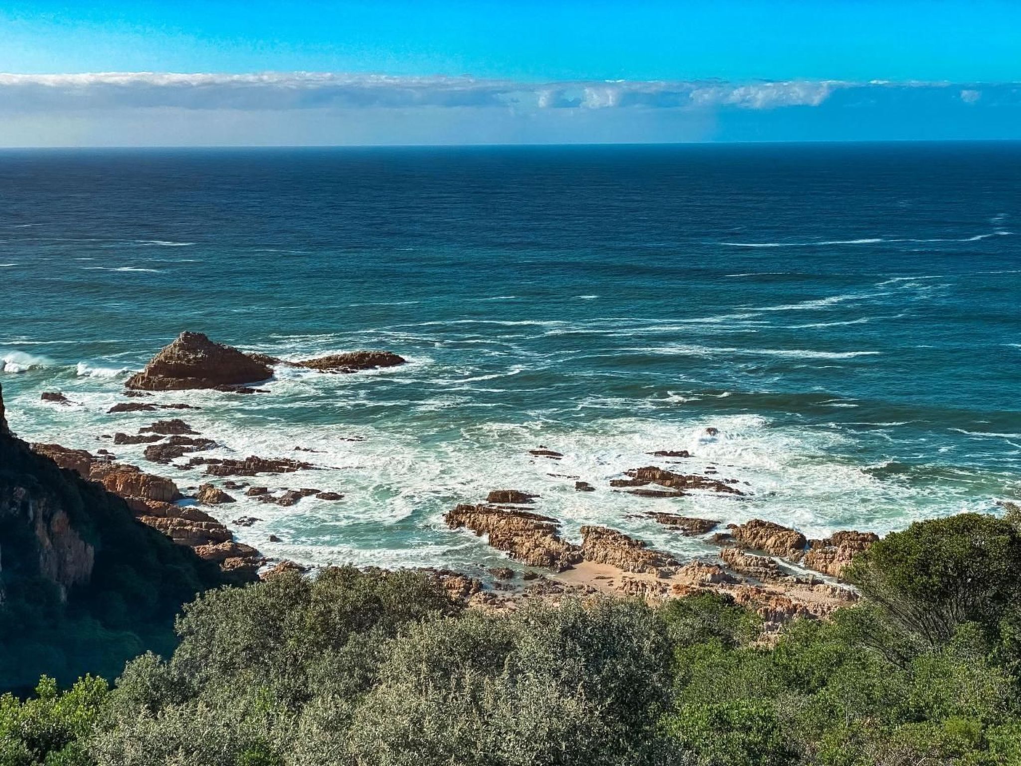 A coastal landscape with rocky outcrops and a view of the ocean.
