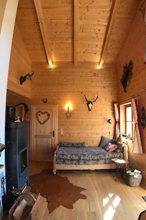 A cozy cabin room with a bed, a fireplace, and wooden walls. - Berghütte mit Blick auf die Berge by Interhome (Rangersdorf)