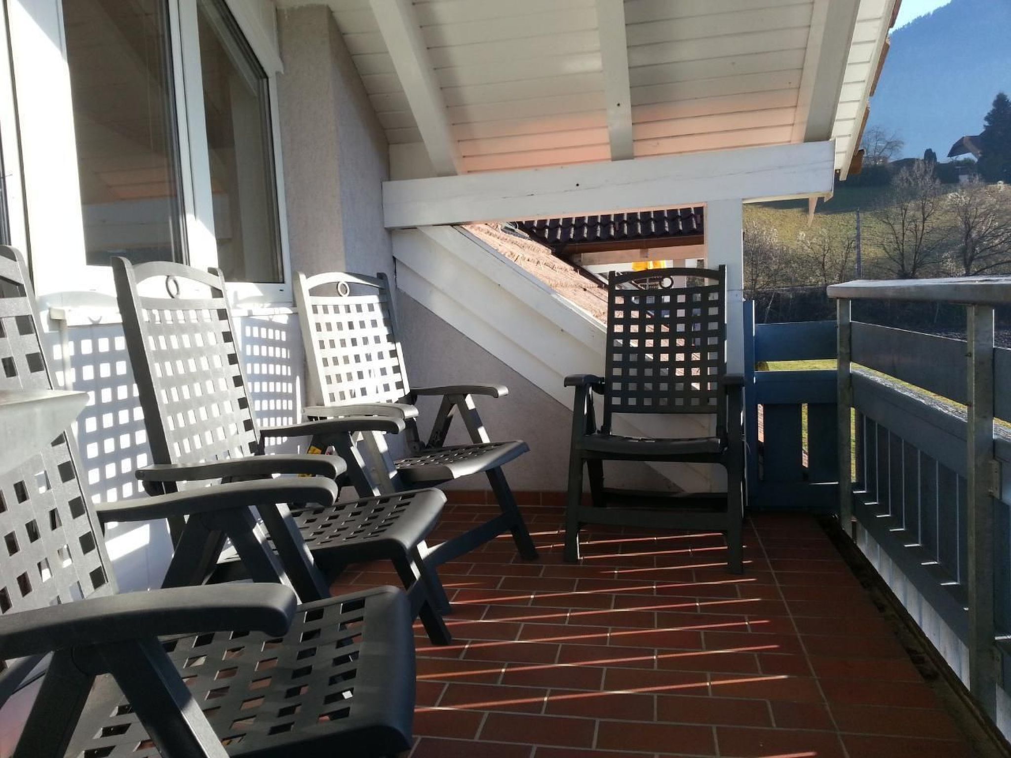 Ein überdachter Patio-Bereich mit Gartenmöbeln, bestehend aus Metallstühlen und einem Tisch.