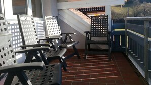 A covered patio area with outdoor seating consisting of metal chairs and a table. - Apartement Feldkirch by Interhome (Feldkirch)