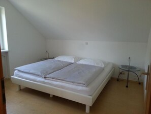 A single-bed room with a sloped ceiling, a small bedside table, and a round table with a lamp. - Apartement Feldkirch by Interhome (Feldkirch)