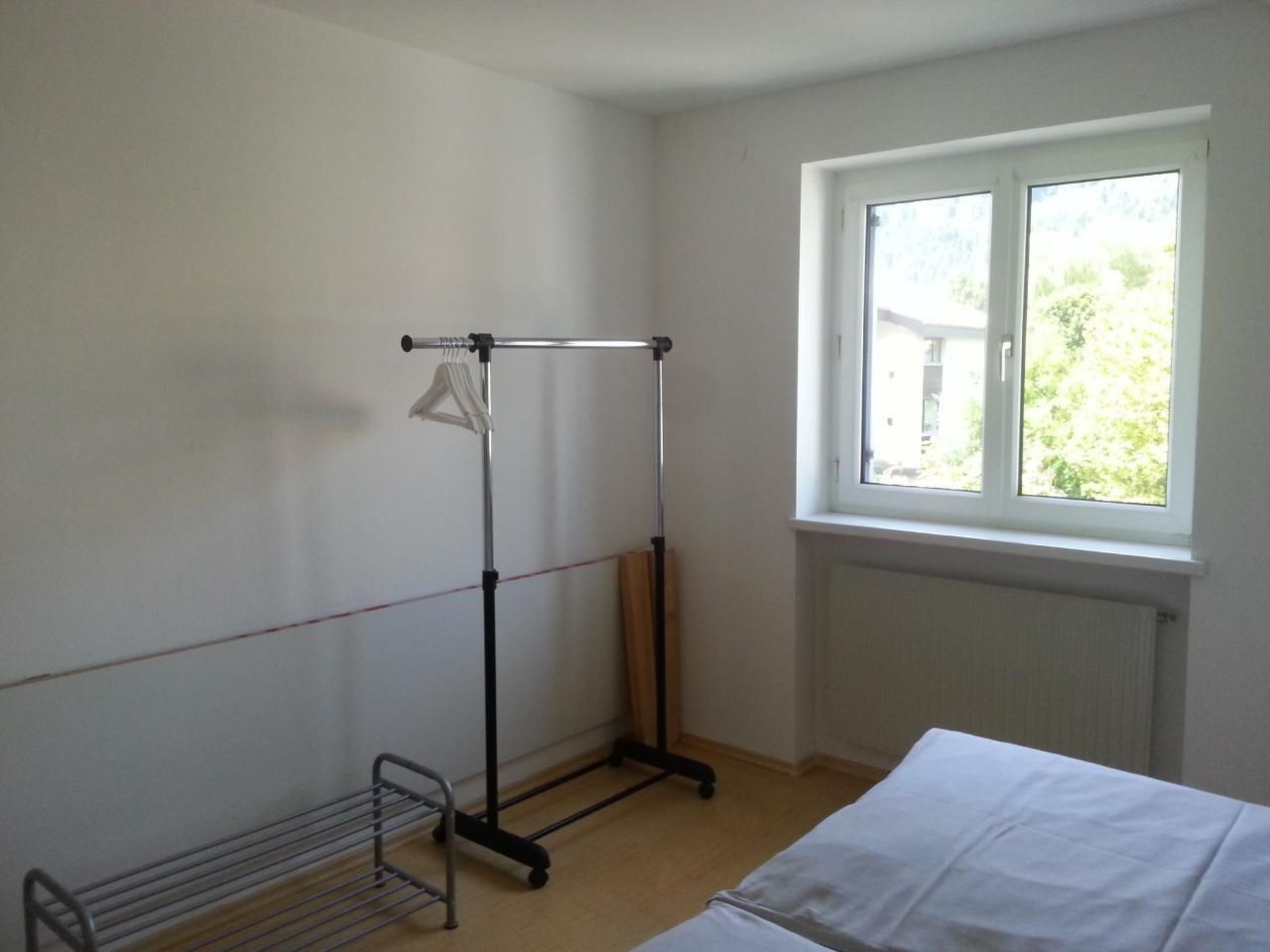 Una habitación con ventana, radiador y un tendedero.