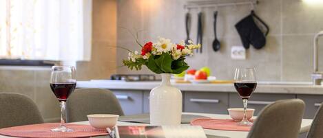 Una cocina moderna con una mesa de comedor para dos personas, con dos copas de vino y un florero con flores.