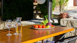 Une table en bois, avec deux verres transparents et une bouteille, une assiette de légumes frais et une lampe en arrière-plan.