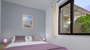 Une chambre à coucher avec un lit, deux lampes de chevet, une fenêtre avec des rideaux et un tableau au mur.