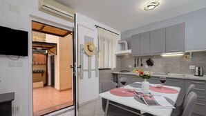 Une cuisine moderne avec des meubles de couleur grise, une table à manger avec des chaises et un téléviseur fixé au mur.