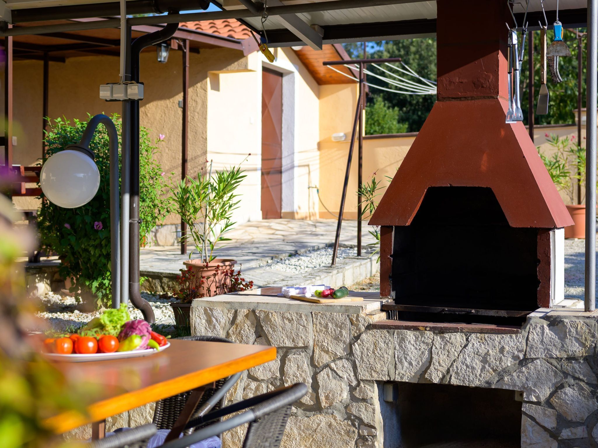 Une terrasse extérieure avec une table en pierre, une petite plante en pot et un four en briques.