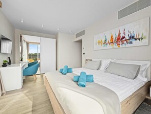 Ein modernes Hotelzimmer mit Bett, Schreibtisch, Stuhl und Balkonblick.