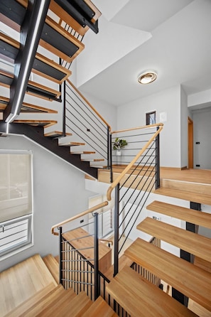 Eine moderne Treppe mit Holzboden und Metallgeländern, die zu einer oberen Etage führt.