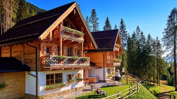 Eine Holzhütte mit Balkon, Steinfundament und Holzzaun.