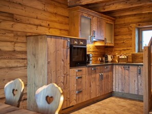 Ein Holzblockhaus-Innenraum mit Küchenzeile, inklusive Kühlschrank, Herd, Mikrowelle und Schränken.