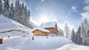 Eine Holzhütte, umgeben von schneebedeckten Bäumen und einer verschneiten Landschaft.