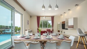 A dining area with a large table set for six, surrounded by modern chairs. - Villa Magnolia by Interhome (Pula)