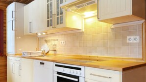 A kitchen with white cabinets, a wooden countertop, a built-in oven, and a range hood.