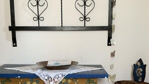 Ein kleiner, dekorierter Tisch mit einer Spitzenleinentischdecke, einer Ziervase und gemusterten Teppichen auf Holzdielen.