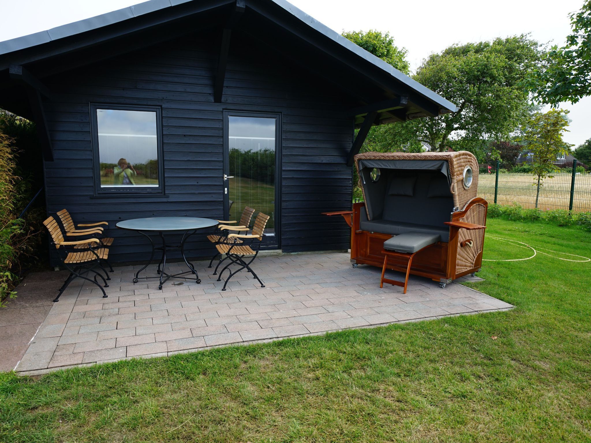 A modern outdoor seating area with a table and chairs, a wooden deck, and a unique wicker sofa.