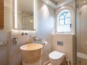 Une salle de bain avec un grand lavabo en bois, des toilettes blanches et une douche à parois de verre.