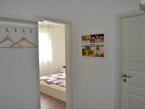 Ein Schlafzimmer mit einem Bett, einem Kleiderschrank mit Kleiderbügeln und einer Tür mit einem Poster.