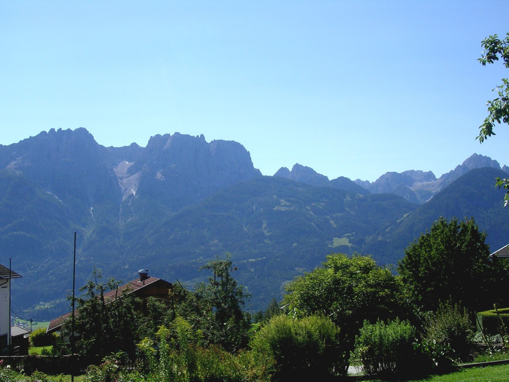 Eine Berglandschaft mit einem Haus im Vordergrund.
