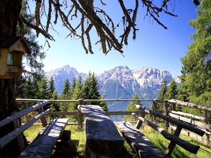 A wooden deck with benches overlooking a mountain range.