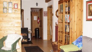 A cozy living room with a fireplace, a green chair, a grey sofa, and a wooden bookshelf. - am Wallnerhof in Flattach by Interhome (Flattach)