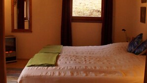 A bedroom with a bed, a window with curtains, a mirror, and a radiator. - am Wallnerhof in Flattach by Interhome (Flattach)