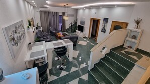 A modern living room with a sofa, a coffee table, and a TV. There is a staircase leading to another level. - mit privatem Pool und Sauna by Interhome (Crikvenica/Jadranovo)