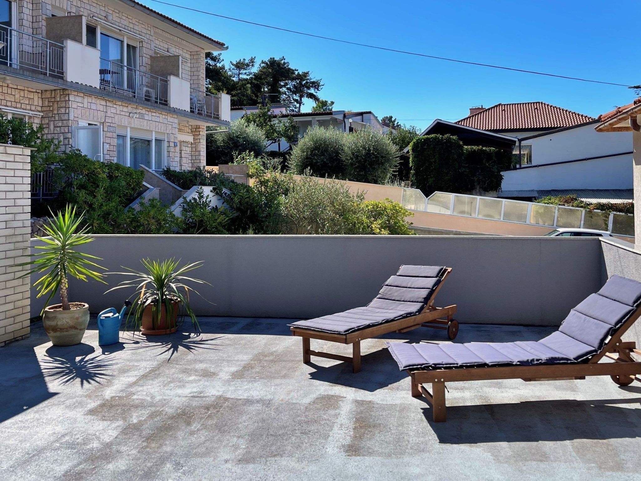 Une terrasse sur le toit, avec deux fauteuils en bois et des plantes en pot.